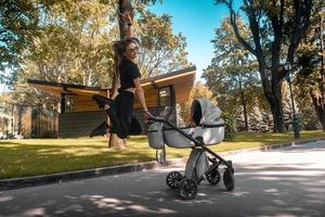 Cheerful stylish young mother flying about the stroller photo
