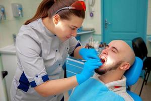 mujer dentista trata dientes paciente foto