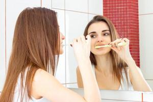 una mujer joven cepillándose los dientes foto