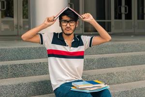 tipo gracioso sentado en la calle y guarda un libro en tu cabeza foto