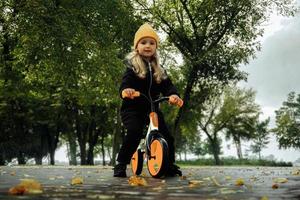 Cutie little girl rides on bicycle at the park photo
