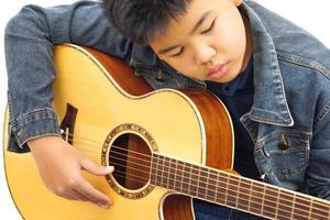 Focus on the hands of the child or teenager playing acoustic guitar on white background. Learning and relax concept. photo