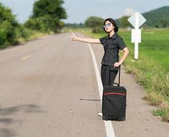 Woman short hair with luggage hitchhiking and thumbs up photo