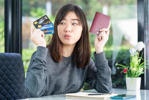 Young woman sitting showing passport and credit card photo