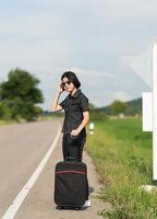Woman with luggage hitchhiking along a road photo