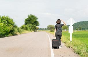 mujer con equipaje haciendo autostop por una carretera foto