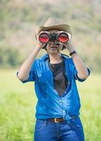 mujer use sombrero y sostenga binocular en el campo de hierba foto