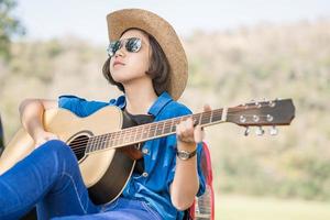 Close up woman wear hat and playing guitar photo