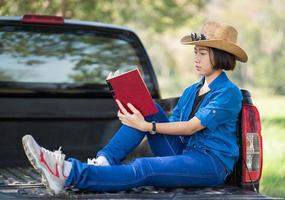 Woman wear hat and reading the book on pickup truck photo