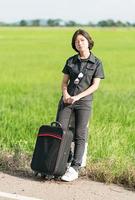 Woman with luggage hitchhiking along a road photo