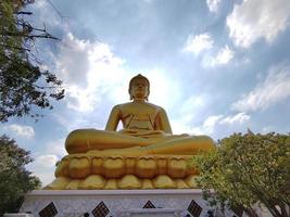 Golden big Buddha statue Phra Buddha Dhammakaya Thep Mongkol in Wat Pak Nam Phasi Charoen temple. Sunlight sky and cloud background