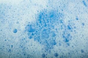 Blue water covered with foam and bubles of shampoo photo