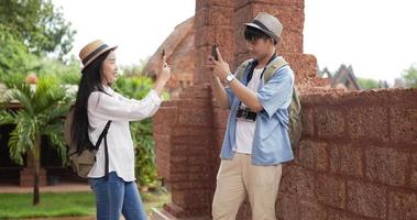 Side view of Happy traveler couple take a photo at ancient temple. Young woman take a picture to boyfriend. Man shooting girlfriend. Male and female selecting photo. Holiday, travel and hobby concept. video