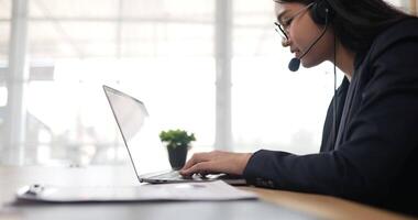 vue latérale de lunettes de femmes heureuses porte un casque d'appel vidéo sur un ordinateur portable. conférencier webinaire de femme d'affaires diffusant une formation Web en direct. agent du centre d'appels, responsable du support technique parlant au client. video