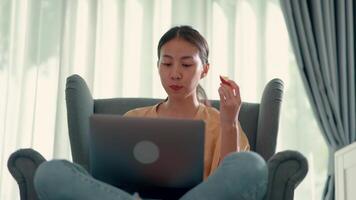 jeune jolie femme assise sur un canapé et mangeant une pomme tout en tapant sur un ordinateur portable, nouveau concept normal et travaillant à domicile video