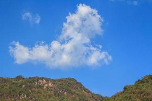 Clouds like poodle dogs float in the air in the clear sky and warm sunlight during the day and the surrounding mountains are full. photo