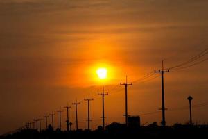 atmosphere in the evening-high voltage pole beside highway and orange sky The big sun that was setting was beautiful as I was on my way home, it was a beautiful romantic atmosphere. photo