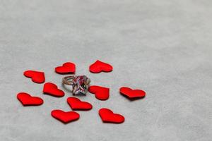 Will you marry me. Wedding ring many red hearts on concrete stone grey background. Engagement marriage proposal wedding concept. St. Valentine's Day postcard. Banner on valentines day. photo