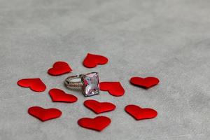 Will you marry me. Wedding ring many red hearts on concrete stone grey background. Engagement marriage proposal wedding concept. St. Valentine's Day postcard. Banner on valentines day. photo