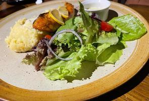 smoked grilled salmon fish served with salad and mash potatoes with lemons photo