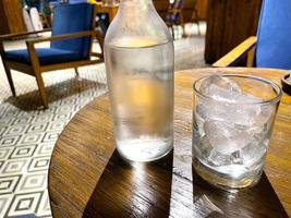 refreshing cold vodka in the bottle with ice rocks in the glass served in the pub photo