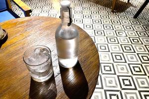 refrescante vodka frío en la botella con rocas de hielo en el vaso servido en el pub foto