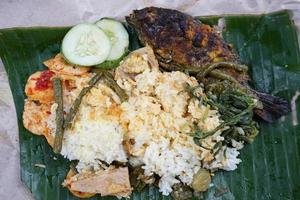 rice wrapped in grilled fish, cucumber, long beans, sweet potato shoots, jackfruit, and crackers photo