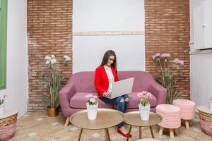 Woman sitting on couch at table and working on notebook photo