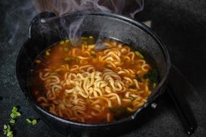 Spicy Korean Instant Noodles with Wakame Seaweed in a Black Iron Pot, Korean Food Traditional Style photo