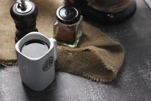 Washington, USA - September 30 2022 - Starbucks Ceramic Mug. Put on the gray table and coffee machine, coffee pot, coffee grinder, ground coffee beans. photo