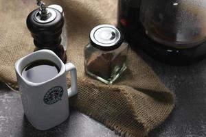 Washington, USA - September 30 2022 - Starbucks Ceramic Mug. Put on the gray table and coffee machine, coffee pot, coffee grinder, ground coffee beans. photo