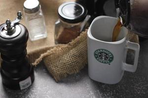 Washington, USA - September 30 2022 - Starbucks Ceramic Mug. Put on the gray table and coffee machine, coffee pot, coffee grinder, ground coffee beans. photo