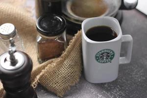 Washington, USA - September 30 2022 - Starbucks Ceramic Mug. Put on the gray table and coffee machine, coffee pot, coffee grinder, ground coffee beans. photo