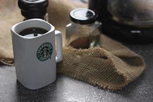 Washington, USA - September 30 2022 - Starbucks Ceramic Mug. Put on the gray table and coffee machine, coffee pot, coffee grinder, ground coffee beans. photo