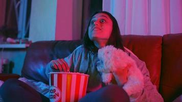 une femme réagit au film alors qu'elle est assise sur un canapé avec du pop-corn video