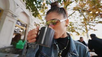 femme avec une tasse de café et des lunettes de soleil à la table de café en plein air video