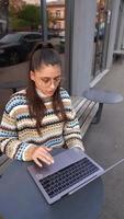 donna seduto al di fuori a caffè negozio con il computer portatile video