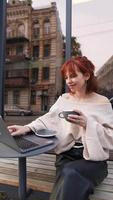 Woman seated outside at coffee shop with laptop video