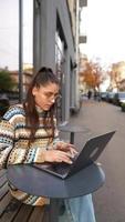 kvinna sittande utanför på kaffe affär med bärbar dator video