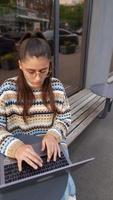 Woman seated outside at coffee shop with laptop video