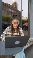 mujer sentada afuera en una cafetería con laptop video