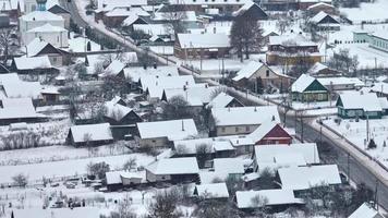 Winterpanoramablick auf das Dorf mit Häusern, Scheunen und Schotterstraße mit Schneefall