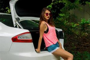 beautiful girl stands near the trunk of the car photo