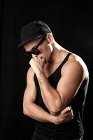 Strong muscular man in sunglasses on black background photo