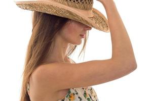 Portrait of a young brunette who covers her face and hat stands sideways isolated on a white background photo