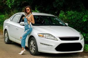 attractive women in jeans dress stands near the white car photo