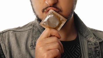 Sexy unshaved gay man with condom in his mouth photo