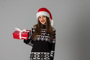 woman in warm sweater and santa hat with red gift photo