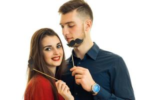 cheerful couple smiling and having fun with paper mustache in hands photo