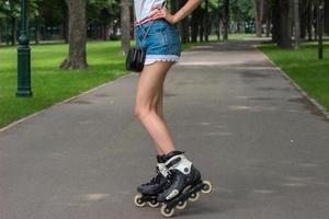 Piernas delgadas de una joven con pantalones cortos de mezclilla que ruedan por el parque foto